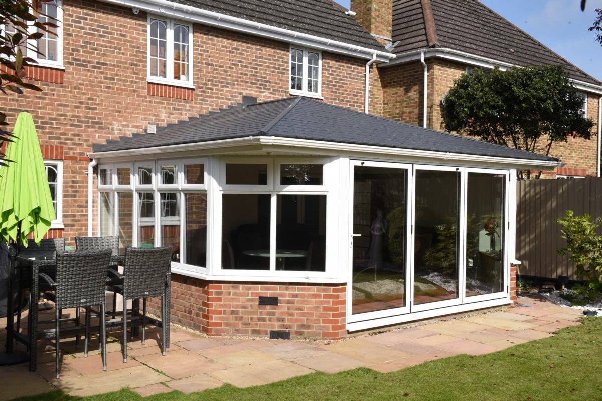 A side on view of a tiled roof extension with a garden.